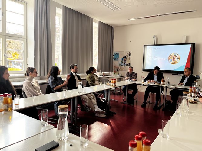 Conrad Clemens (Sächsischer Staatsminister für Kultus) und Jörg Heynoldt (Leiter LaSuB SO Leipzig) an der Schule Ratzelstraße vor einer Interaktiven Tafel, an einem Quadrat aus Tischen.sitzend.