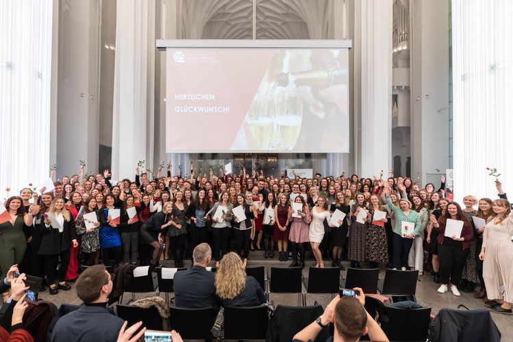 Viele Menschen stehen für ein Gruppenfoto vor einer Präsentation.