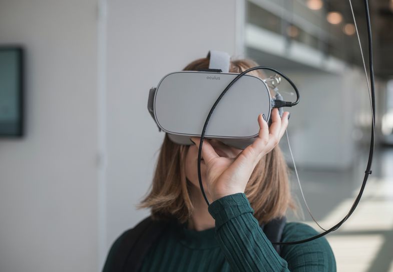 Eine Frau schaut durch eine VR Brille. Foto: Maxim Hopman / Unsplash.