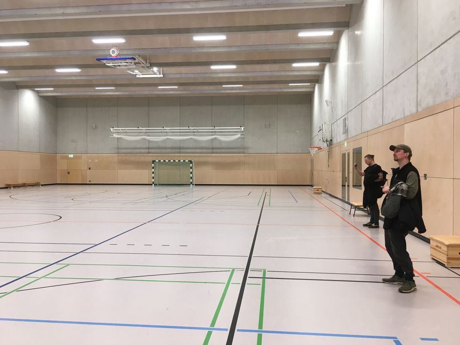 zur Vergrößerungsansicht des Bildes: Zwei Personen sehen sich eine leere Sporthalle an. 
