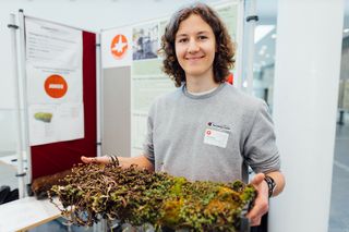 Das Foto zeigt eine junge Person, die im Rahmen des Jugend forscht Wettbewerbs vor einem Projektstand posiert. 