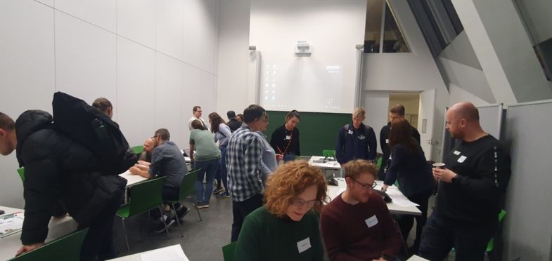 Personen tauschen sich in einem größeren Raum in kleinen Gruppen aus. 