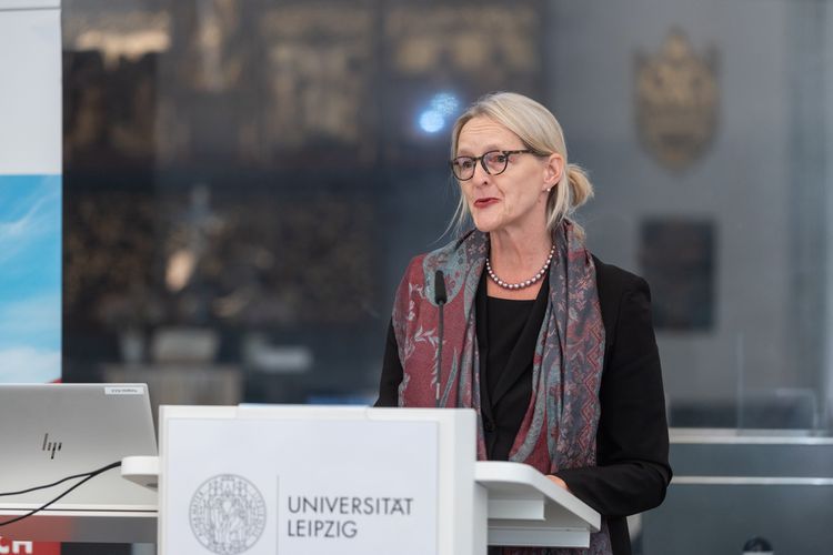 Eine Frau steht an einem Rednerpult und spricht.